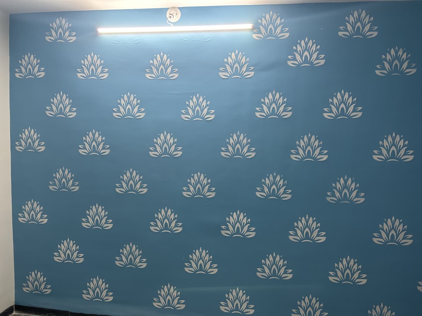 Hand-stenciled silver lotus motif on a deep blue accent wall