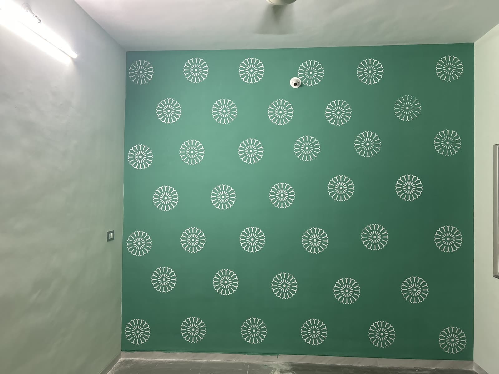 Hand-stenciled dandelion motif covering a full sage-green feature wall